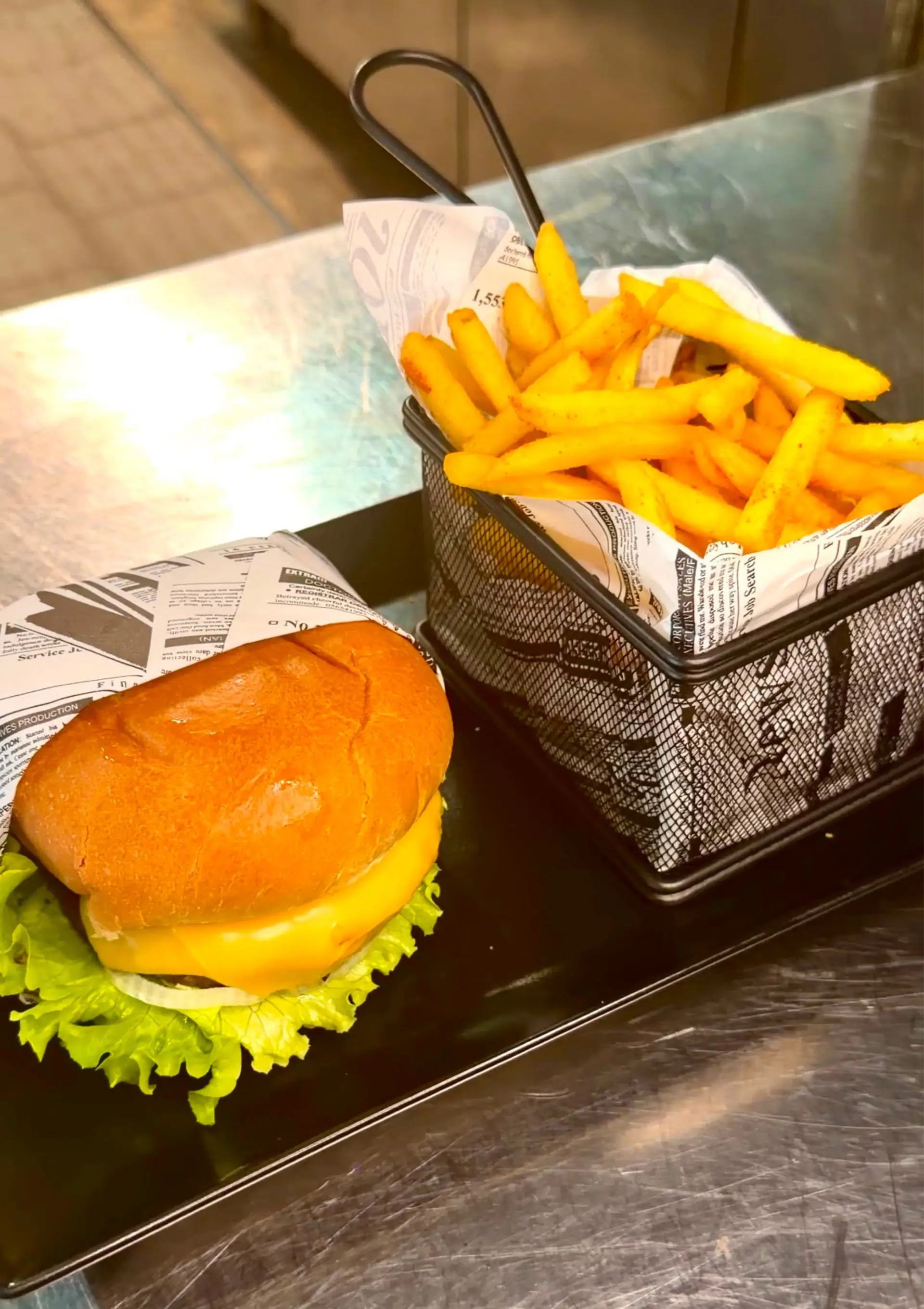 A cheeseburger with a basket of seasoned fries served on a tray at Zazoo