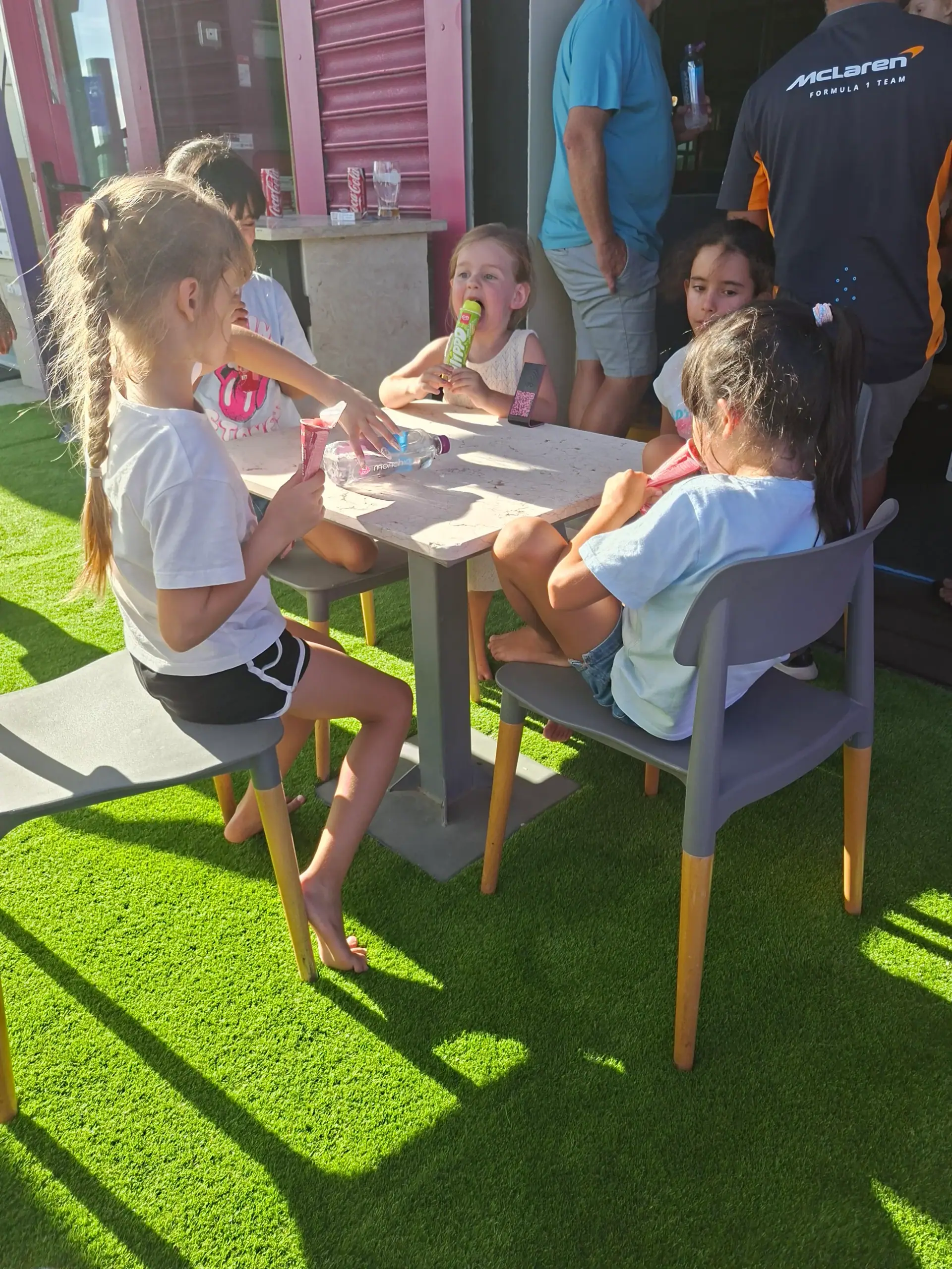 Children enjoying ice lollies together at Zazoo's outdoor terrace tables