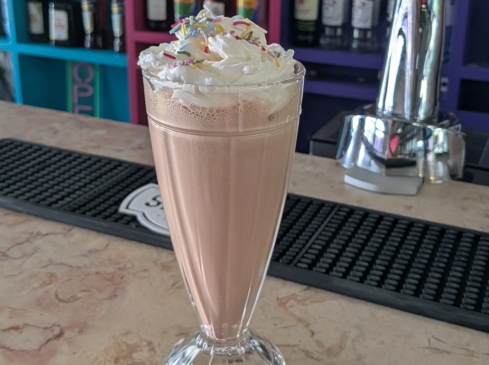 A chocolate milkshake topped with whipped cream and sprinkles at Zazoo's bar