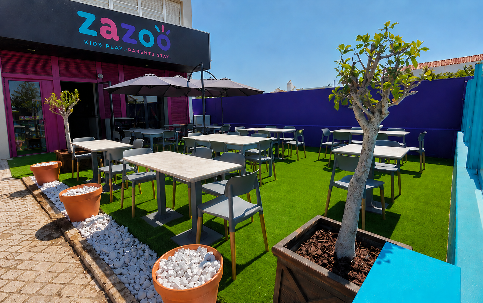 The freshly revamped front of Zazoo: bright brand colours, astro turf and a sunny terrace of tables in Almancil